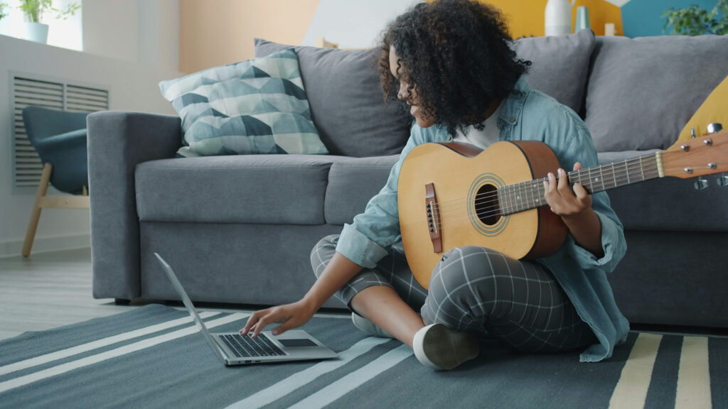 Guitarist sitting on floor playing guitar while using the Take Stage app.